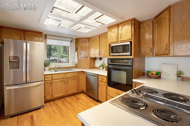 kitchen featuring black appliances, light wood-style flooring, light countertops, and a sink