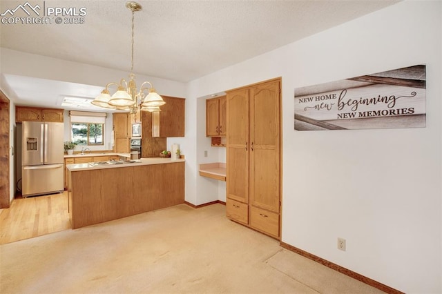 kitchen with stainless steel appliances, a peninsula, a sink, light countertops, and pendant lighting