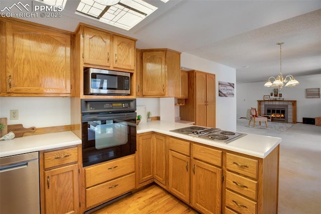 kitchen featuring appliances with stainless steel finishes, brown cabinets, open floor plan, light countertops, and pendant lighting