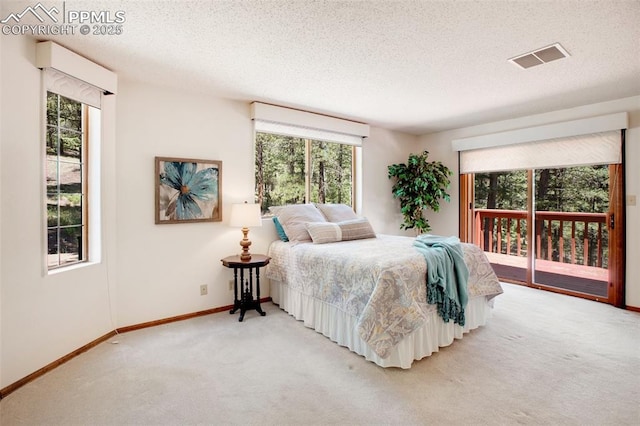 carpeted bedroom with access to exterior, visible vents, a textured ceiling, and baseboards