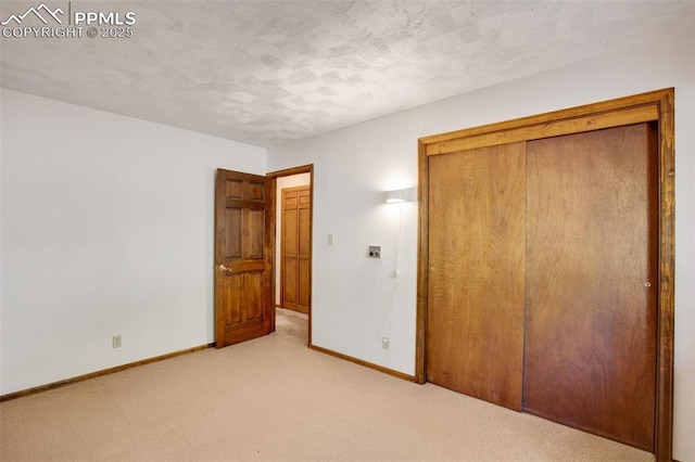 unfurnished bedroom with baseboards, a closet, a textured ceiling, and light colored carpet