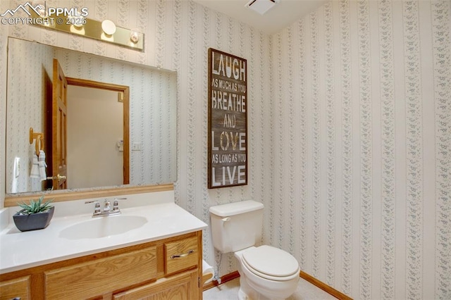 bathroom featuring toilet, wallpapered walls, and vanity