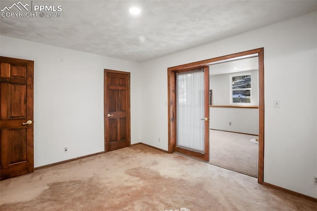 unfurnished room featuring baseboards and light colored carpet