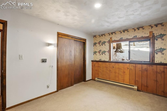 unfurnished bedroom with a baseboard radiator, a closet, light carpet, baseboards, and wallpapered walls