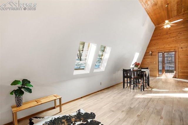 dining room with a skylight, light wood finished floors, wooden walls, high vaulted ceiling, and wooden ceiling