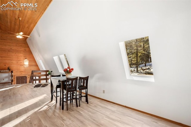 dining room with a skylight, wood ceiling, wood walls, and light wood finished floors