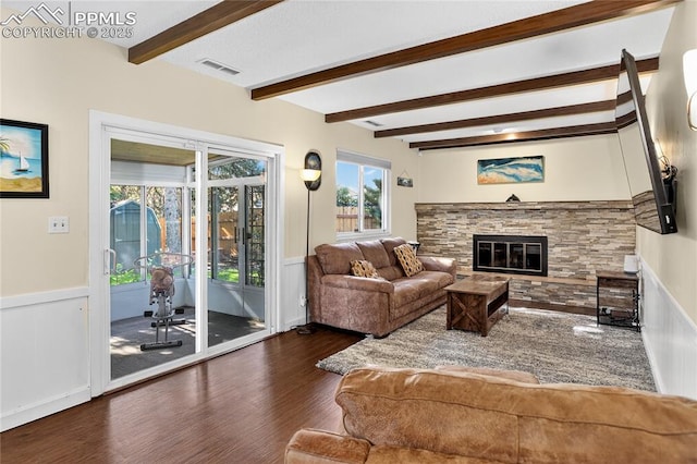 2113 Woodburn St, Colorado Springs, CO 80906 - living area featuring wood finished floors, beamed ceiling, a wainscoted wall, a stone fireplace, and a decorative wall