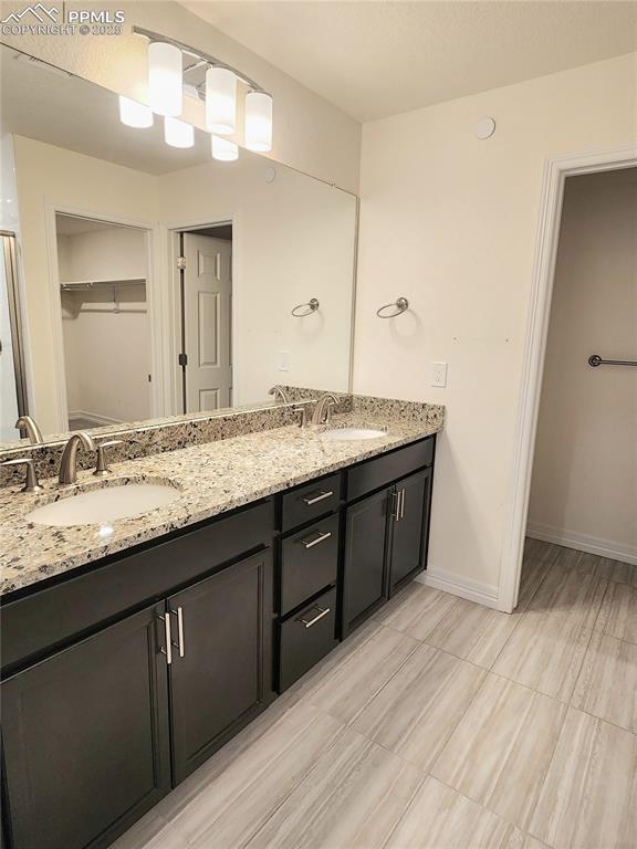 bathroom with double vanity, a sink, and baseboards