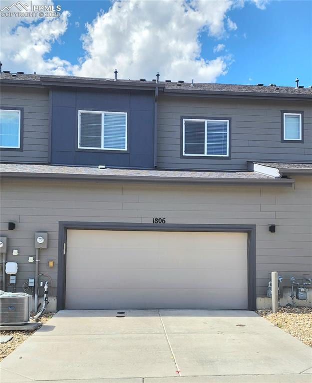 view of front of property with a garage, concrete driveway, and central AC unit