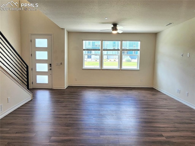 entrance foyer with ceiling fan, dark wood finished floors, a textured ceiling, and stairs