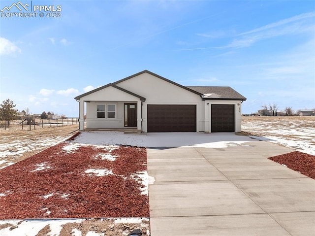 view of front of property with fence, stucco siding, an attached garage, and concrete driveway