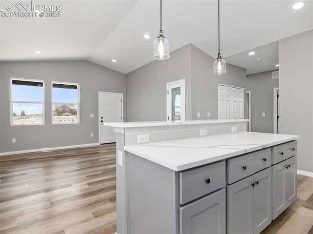 kitchen featuring a center island, decorative light fixtures, gray cabinets, light wood-style floors, and lofted ceiling