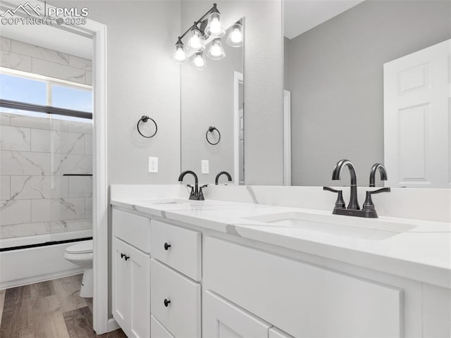 full bath featuring double vanity, shower / washtub combination, wood finished floors, and a sink