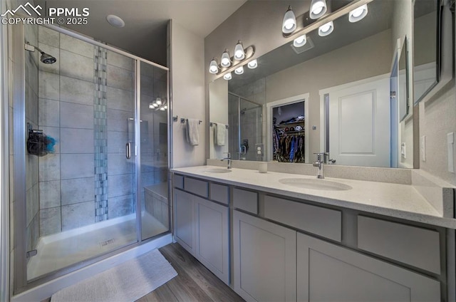 full bathroom with a stall shower, a sink, a spacious closet, and wood finished floors