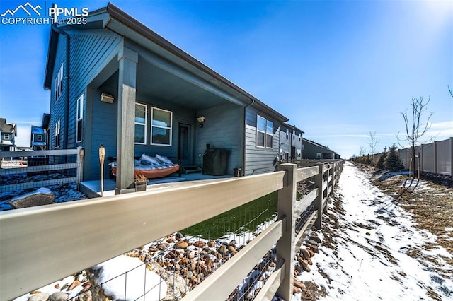 view of snowy exterior with a fenced front yard