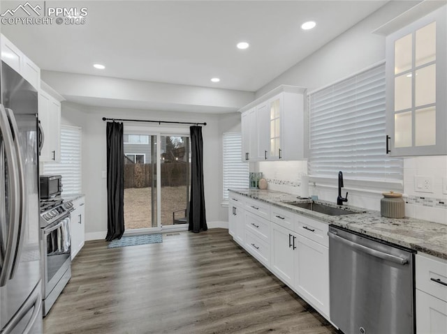 kitchen featuring sink, light stone counters, dark hardwood / wood-style floors, stainless steel appliances, and white cabinets