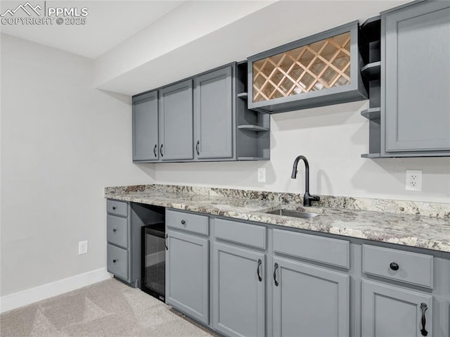 kitchen featuring light colored carpet, sink, gray cabinetry, and beverage cooler