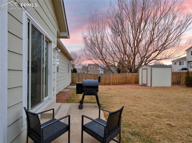 patio terrace at dusk with a storage shed and a lawn