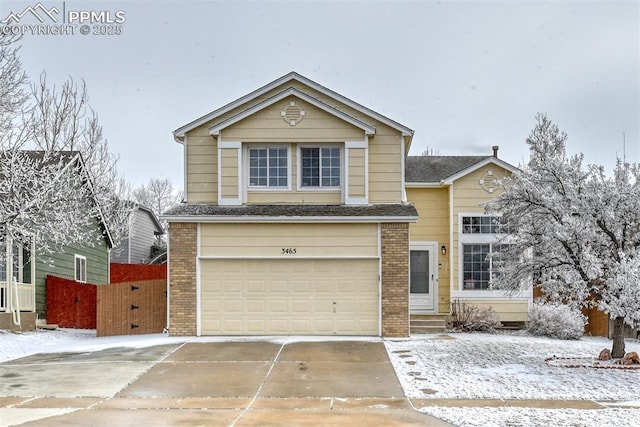 traditional home with brick siding, concrete driveway, an attached garage, and fence