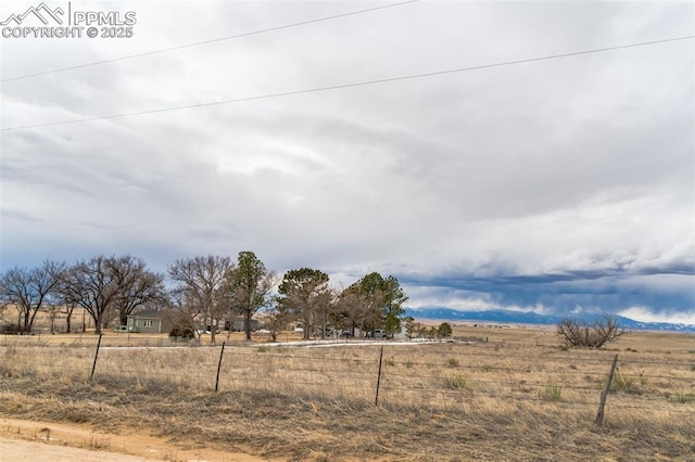 view of yard with fence and a rural view