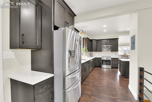 kitchen with stainless steel appliances, recessed lighting, light countertops, dark wood-type flooring, and electric panel