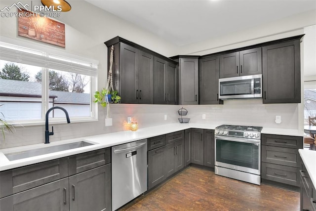 kitchen featuring stainless steel appliances, a sink, light countertops, dark wood-style floors, and tasteful backsplash