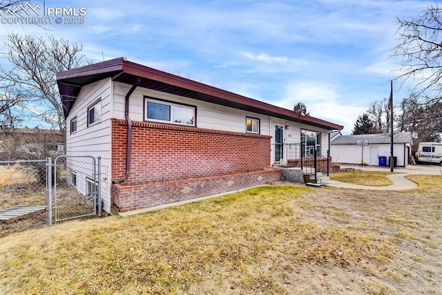 view of front of property with brick siding, a front lawn, fence, and a gate