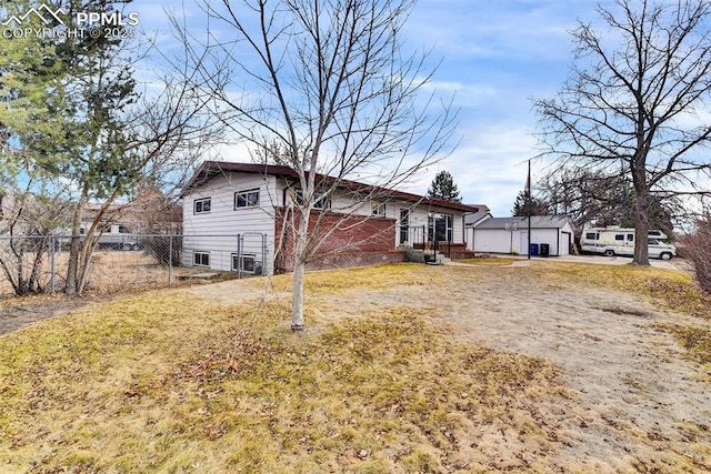 exterior space with brick siding, a lawn, an outdoor structure, and fence