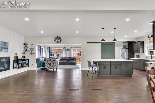 kitchen with a kitchen island, open floor plan, decorative light fixtures, light countertops, and stainless steel refrigerator with ice dispenser