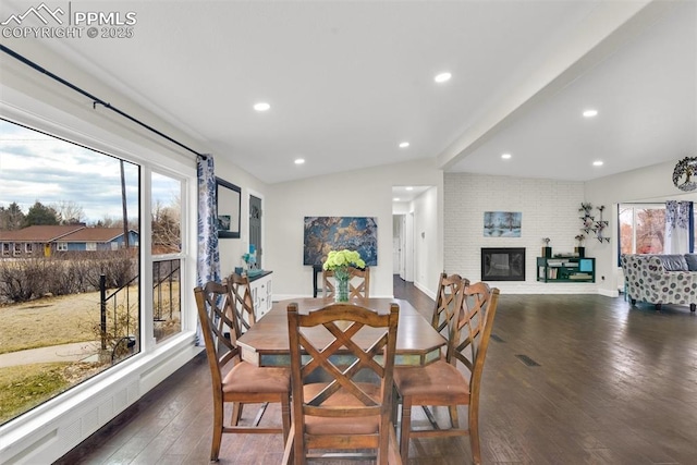 dining space featuring recessed lighting, baseboards, vaulted ceiling, a brick fireplace, and dark wood finished floors