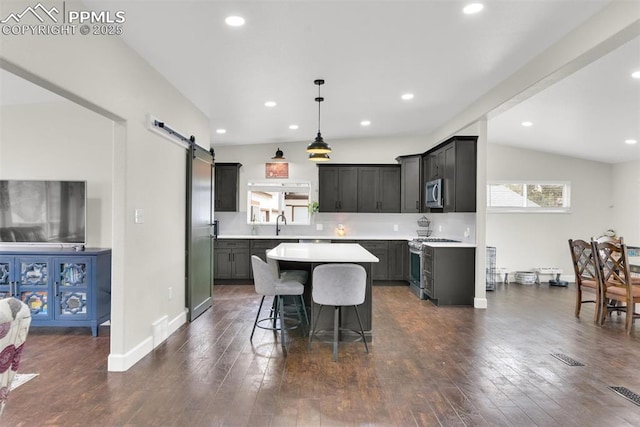 kitchen featuring a center island, light countertops, hanging light fixtures, a barn door, and appliances with stainless steel finishes