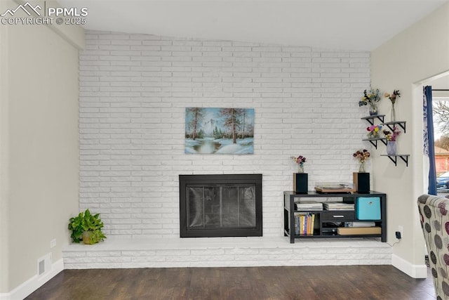 living area with a brick fireplace, baseboards, visible vents, and wood finished floors