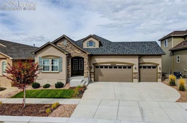 view of front of home featuring driveway, stone siding, an attached garage, and stucco siding