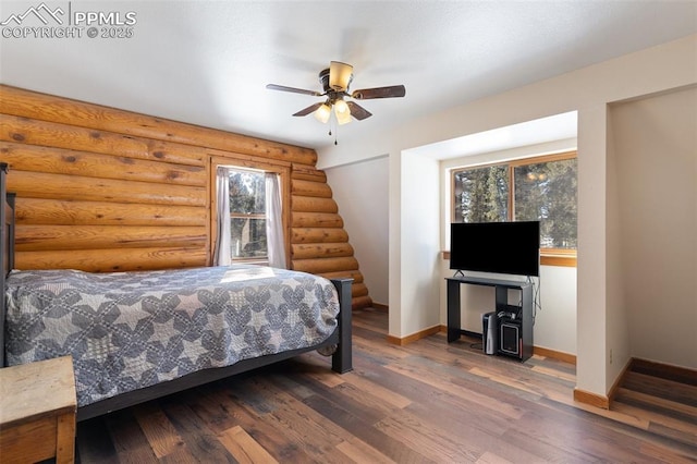 bedroom featuring log walls, ceiling fan, and wood-type flooring