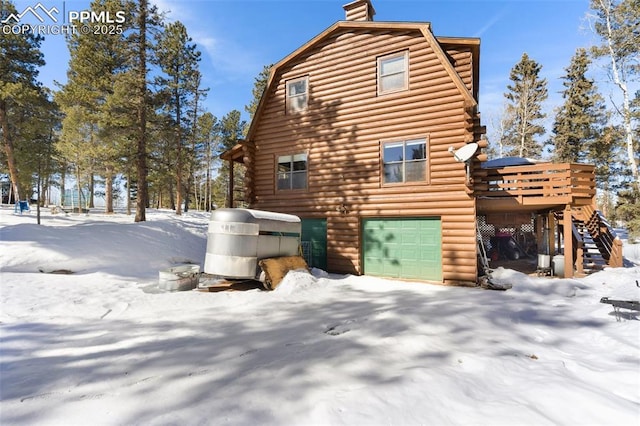 view of snowy exterior featuring a garage and a deck