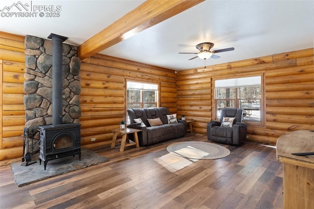 living room featuring a wood stove, dark hardwood / wood-style flooring, a healthy amount of sunlight, and beam ceiling