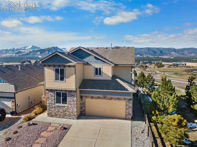 view of front of home with a mountain view, stone siding, and driveway