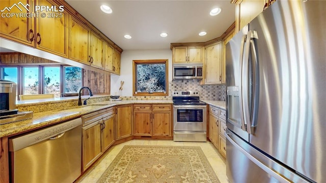 kitchen with appliances with stainless steel finishes, sink, backsplash, light stone counters, and light tile patterned flooring