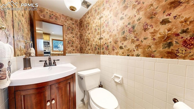 bathroom with tile walls, toilet, and vanity