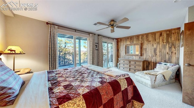 bedroom with carpet, ceiling fan, access to exterior, and wood walls