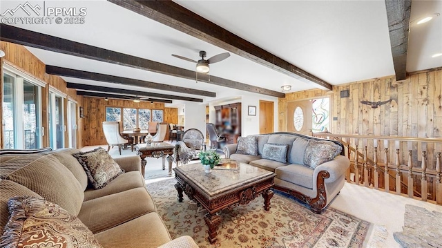 carpeted living room featuring beamed ceiling, wood walls, and ceiling fan