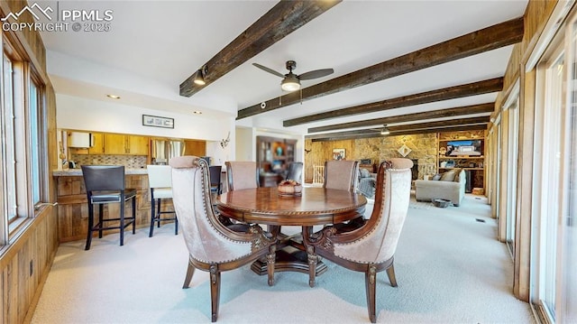 carpeted dining space with ceiling fan and beam ceiling