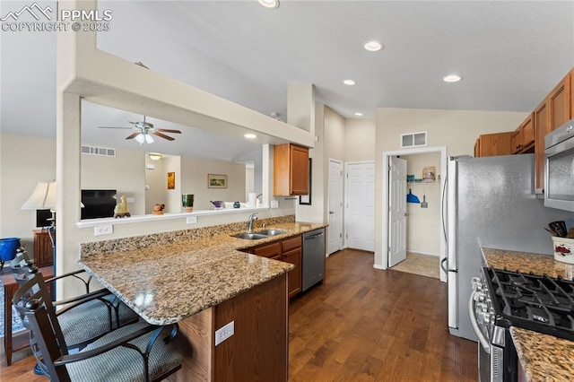 kitchen with appliances with stainless steel finishes, a breakfast bar area, a peninsula, and brown cabinets