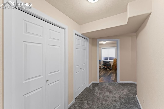 hall with dark colored carpet and baseboards