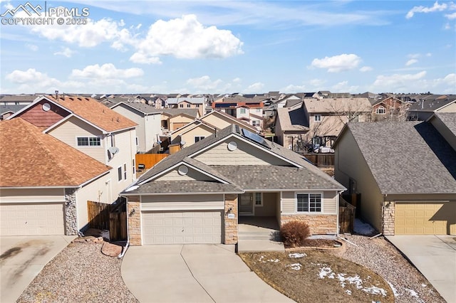 view of front facade with fence, a residential view, stone siding, and concrete driveway