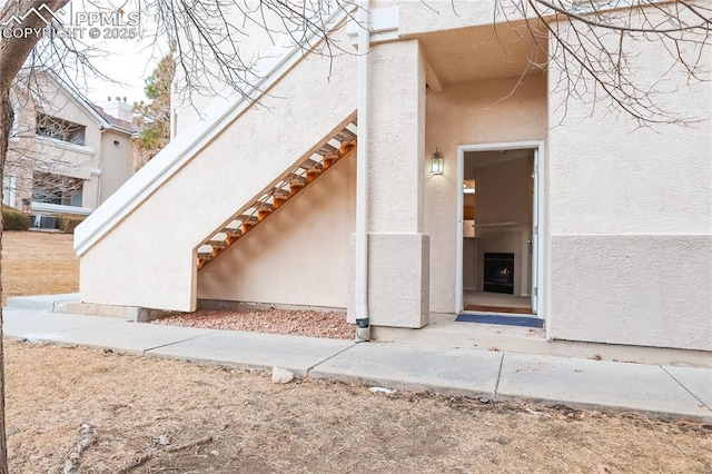 view of exterior entry with cooling unit and stucco siding