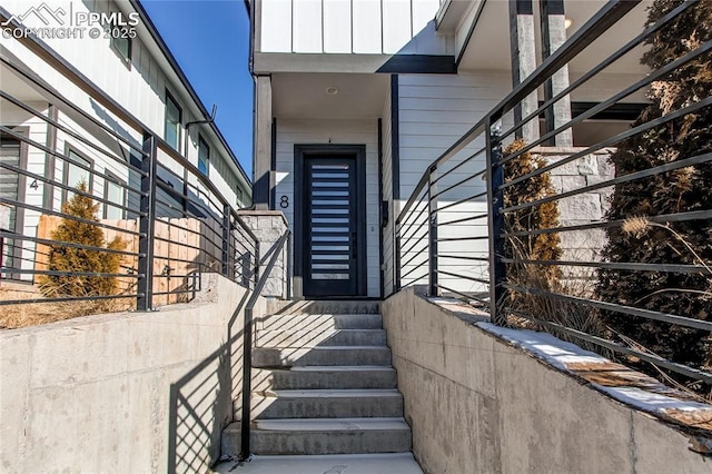 property entrance with board and batten siding and fence