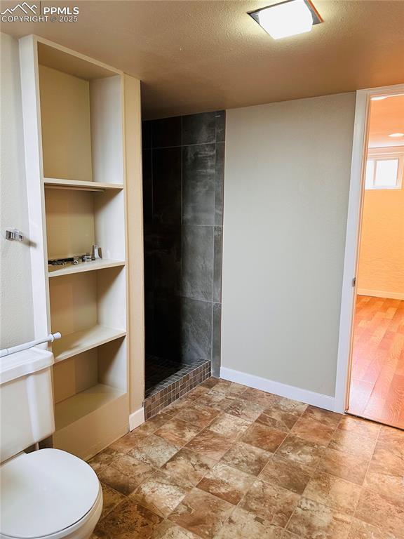 bathroom featuring a tile shower, a textured ceiling, and toilet