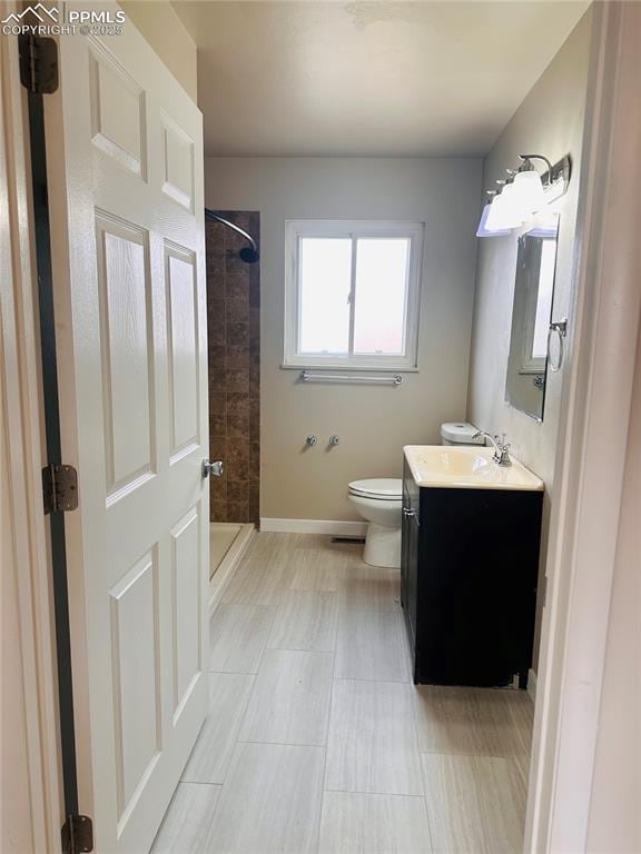 bathroom featuring tiled shower, vanity, and toilet