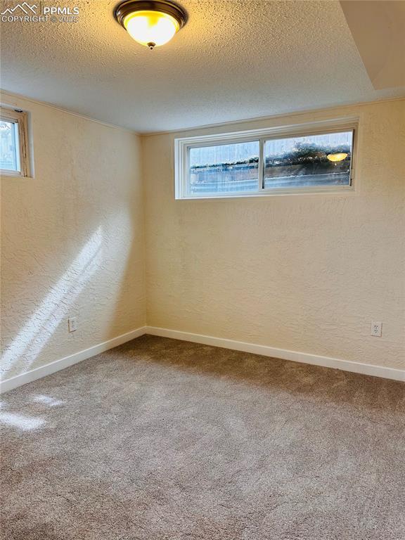 carpeted empty room featuring a textured ceiling